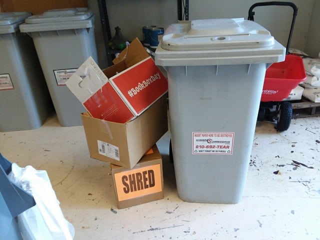 Secure shredding container beside three boxes stacked with the label shred on them