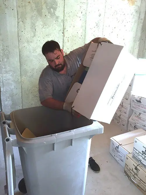 A person emptying a box of documents into a secure collection container