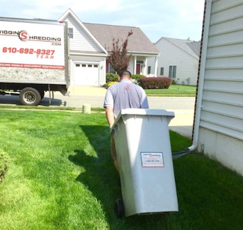 A Wiggins Shredding representative bringing a secure collection container towards the mobile shredding truck