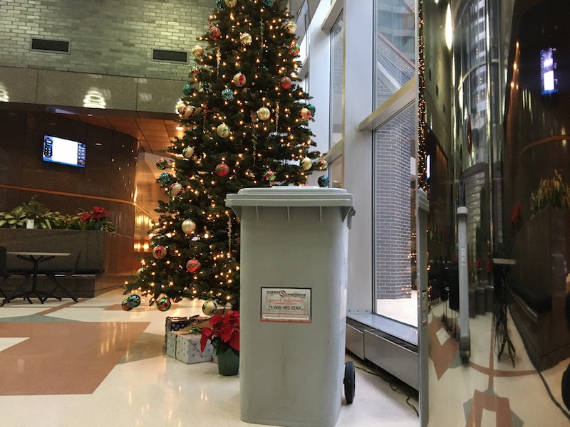 A secure collection container standing infront of a christmas tree