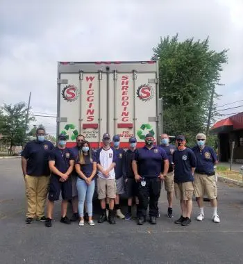 The back of Wiggins Shredding Truck with a group of employees standing in front of it