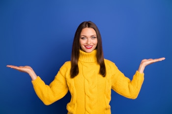 Photo of cheerful positive cute attractive woman holding two things with hands smile toothy holding empty space isolated dark blue color background