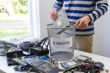A man adding electronics to a bin that reads E-Waste