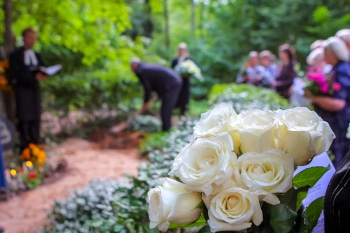 An outdoor funeral with the camera focused on flowers with people in the background