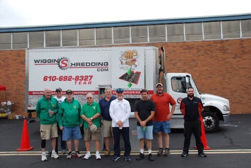 A group of people standing in front of the Wiggins Shredding Truck Posing for the picture