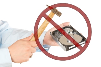 A person taking a hammer to a hard drive with a Do Not Use Symbol above