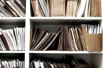 Files and binders on a white shelf in an office setting