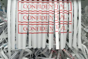 Pieces of paper being shred with the words Confidential on them
