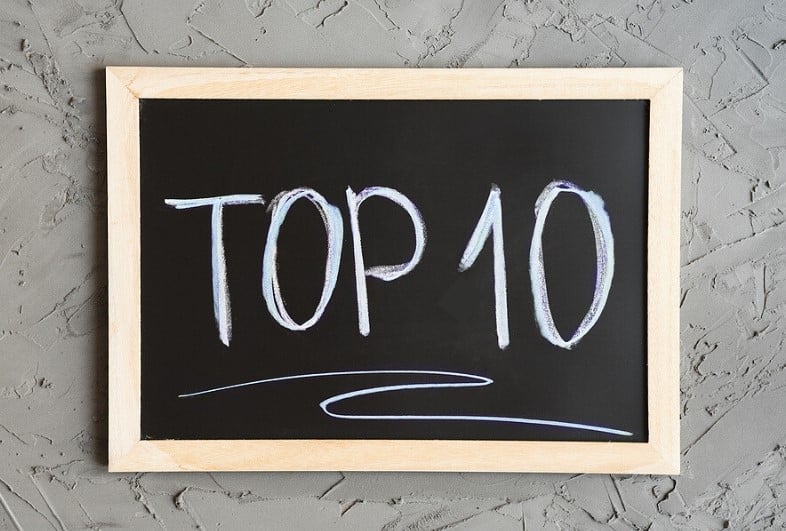 The words "Top 10" are written in white chalk on a black chalkboard which is hung on a grey textured wall.